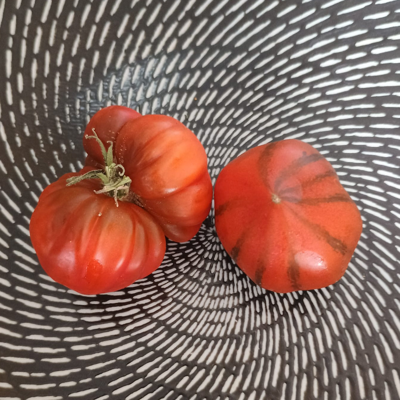 Große, leicht gerippte, rote Frucht der spanischen Fleischtomate (z.B. Montserrat oder RAF), saftig, fleischig, meist 200–300 g schwer, würzig-süßes Aroma, ideal für Salate oder als Brotbelag.